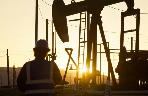 Oilfield Worker Facing Oil Pump Jack at Sunset