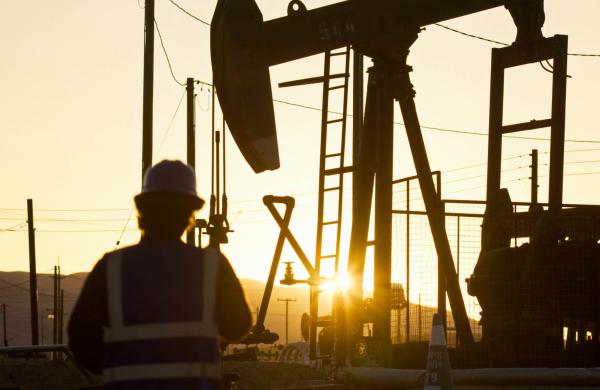 Oilfield Worker Facing Oil Pump Jack at Sunset