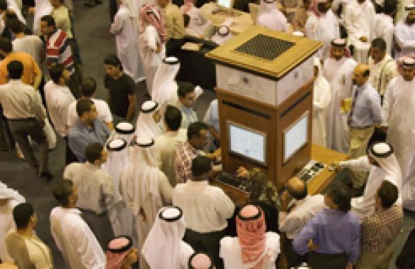 Investors at the Dubai Financial Market, the local Stock Exchange,  gather round the display showing the latest prices.  Dubai. United Arab Emirates. 