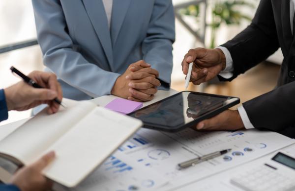 Business consultant meeting is analyzing market situation by financial chart and planning business investment strategy on tablet.