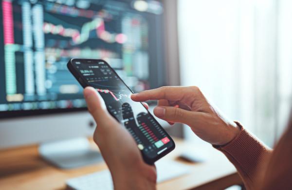 Woman is checking Bitcoin price chart on digital exchange on smartphone, cryptocurrency future price action prediction.