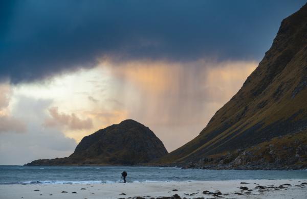 Photographer on the beach on stormy sunset, Lofoten Islands, Norway