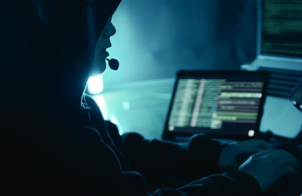 A hacker speaking on headphones and using computer breaks into government data servers and infects their systems with a virus. Cyber crime, Digital system security