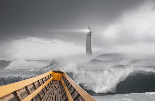 Boat sailing on stormy sea under lighthouse
