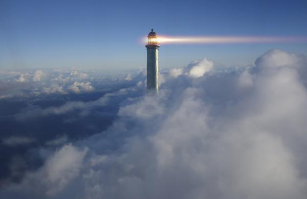 Lighthouse beaming above clouds in blue sky
