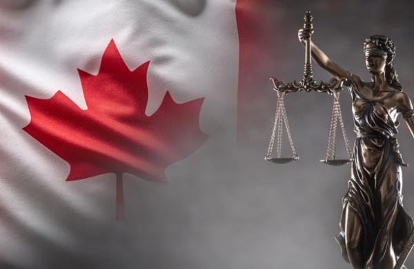 Justice is blind statue symbolizing law with scales and sword in hands and a Canadian  flag in the background.