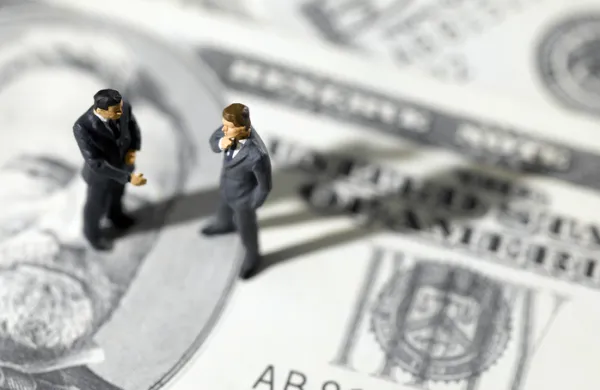 toy businessmen on US paper currency