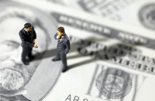 toy businessmen on US paper currency