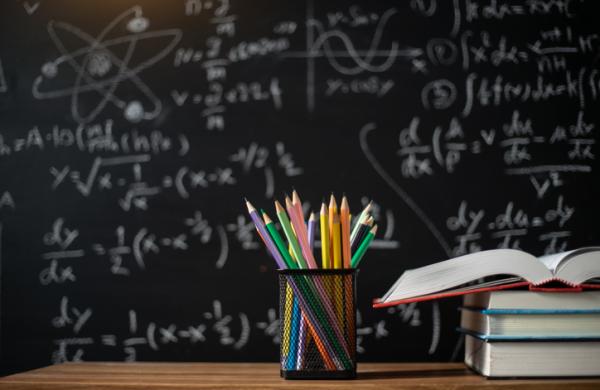 Back to school supplies. Books and blackboard on wooden background,education