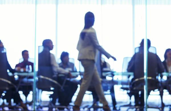 Businesswoman walking in front of colleagues during business meeting in conference room