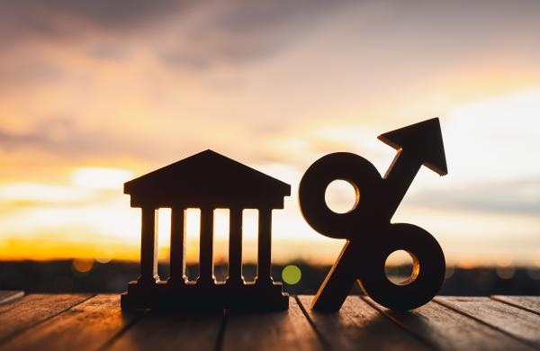 Silhouette of Bank symbol and Percentage model on wood table. Concepts of the banking system, rising interest rates, inflation, deflation, and savings.