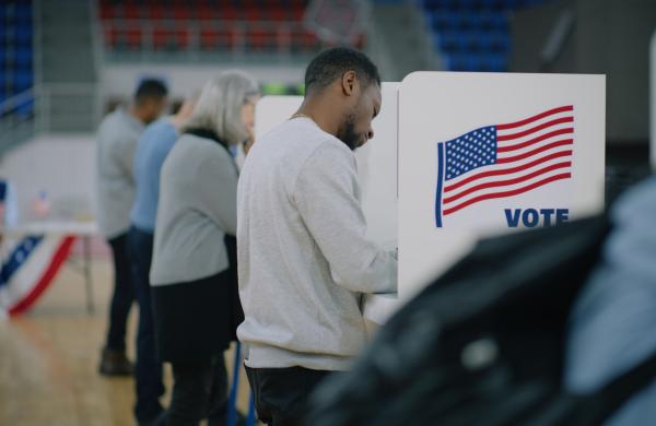 Elderly male voter with bulletin in hands comes to voting booth