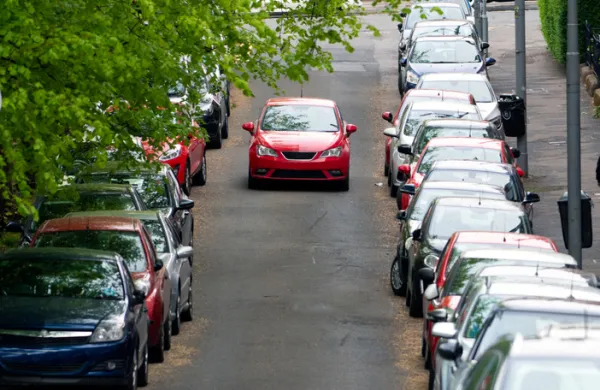 Car in the middle of a road with cars parked on either side, Scotland, UK