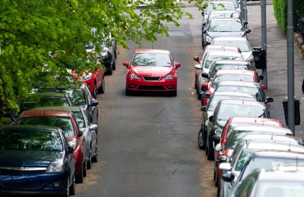 Car in the middle of a road with cars parked on either side, Scotland, UK