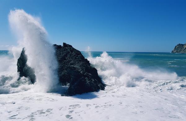Turbulent sea and wave exploding on a rock