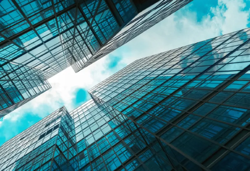 Tall glass skyscrapers reflecting sunlight from a clear blue sky.